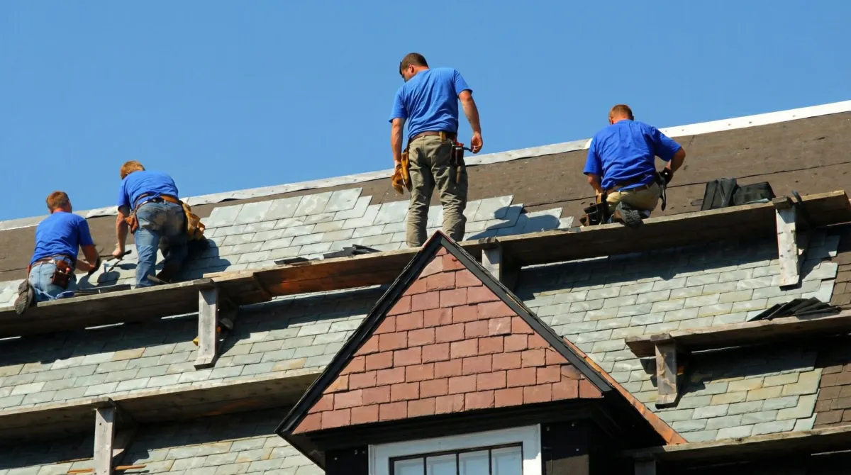 Roof replacement in progress with a team of professional contractors installing new shingles on a residential home in Colorado Springs, CO